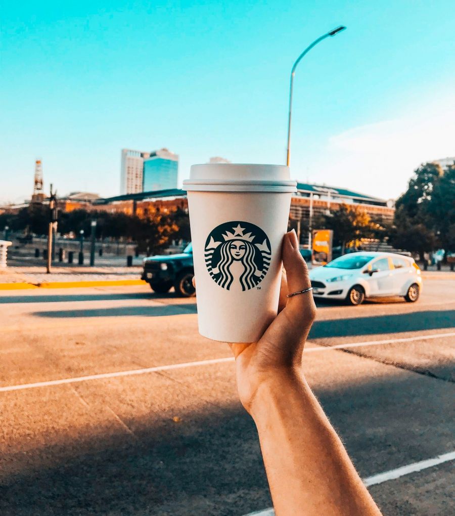 person holding up Starbucks cup to view of downtown Minneapolis