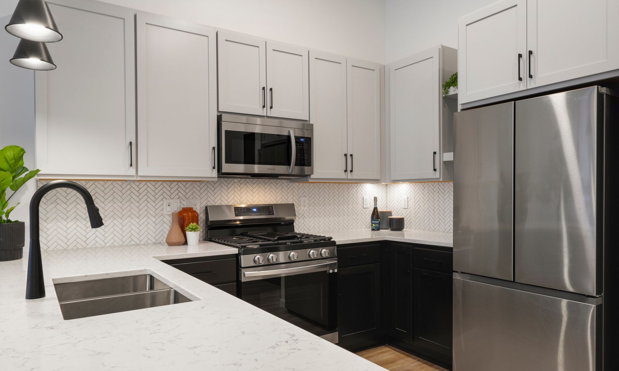 interior photo of Moment Apartments showing kitchen island, stainless steel appliances, gas range, quartz countertops, and kitchen cabinetry